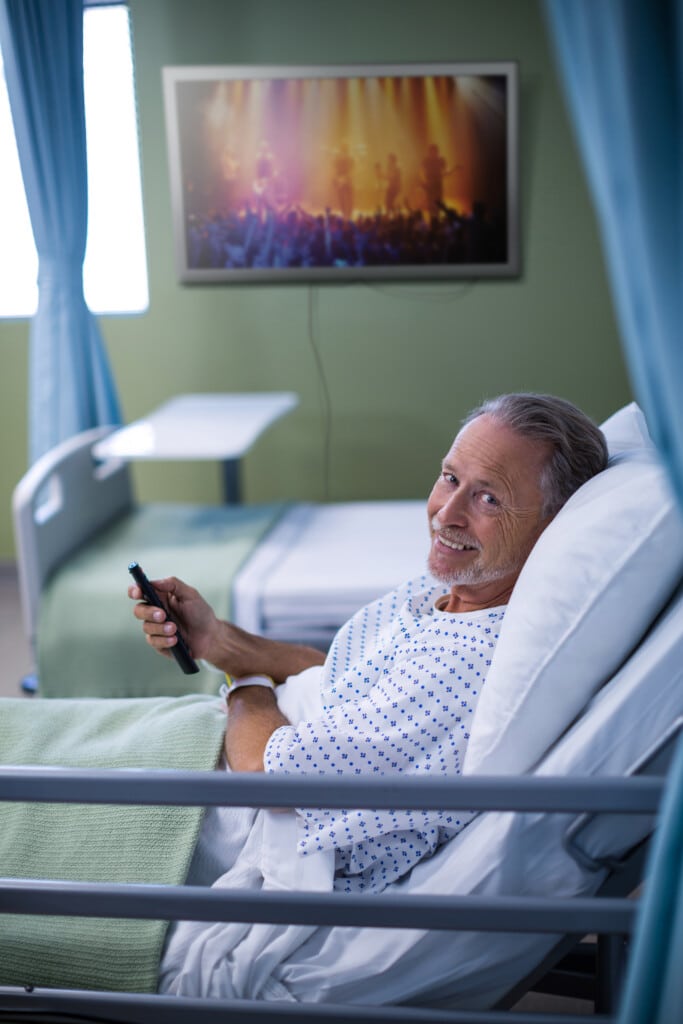 man in hospital bed watching tv